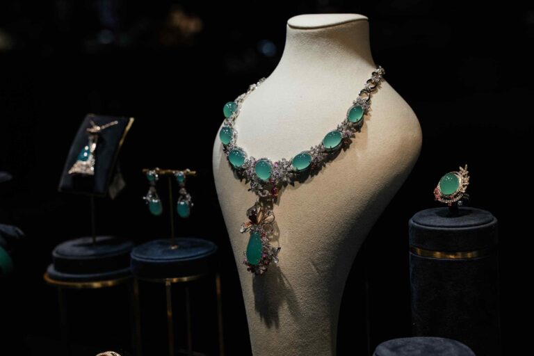 Diamond and emerald-green jadeite necklace displayed on a mannequin bust with matching luxury jewellery against a dark background